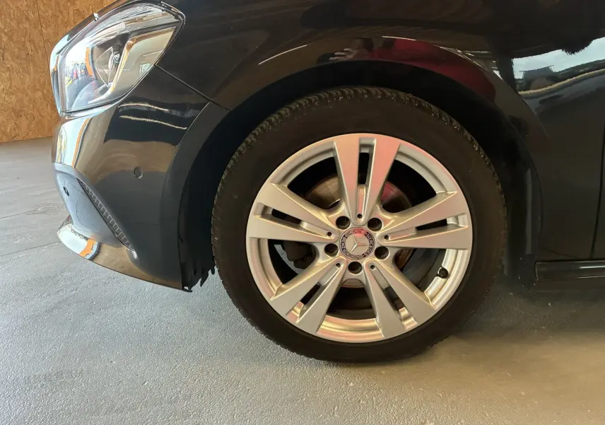 Gros plan sur la roue avant gauche argentée d'une Mercedes Classe A 180 CDI Sensation noire de 2018.