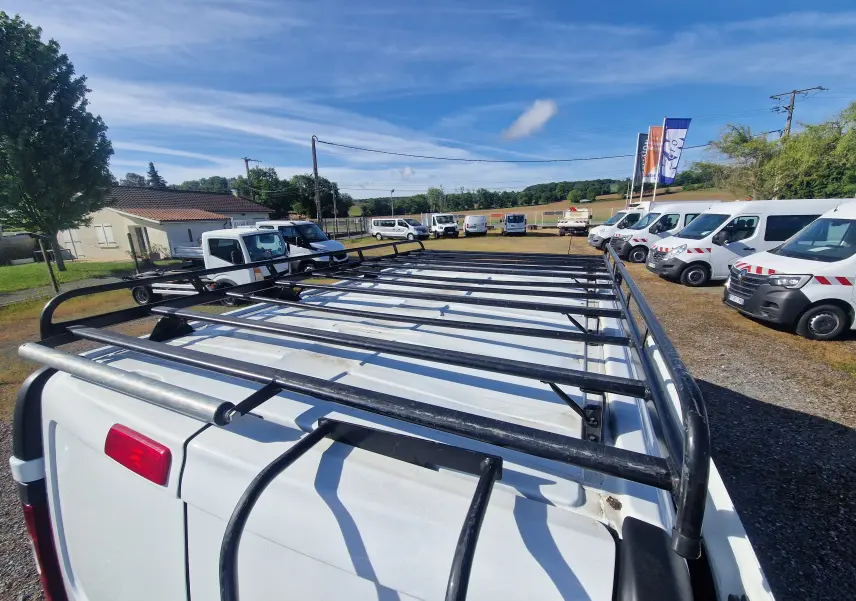 Vue plongeante arrière montrant la galerie noire sur le toit blanc d’un Renault Trafic Fourgon stationné en extérieur.