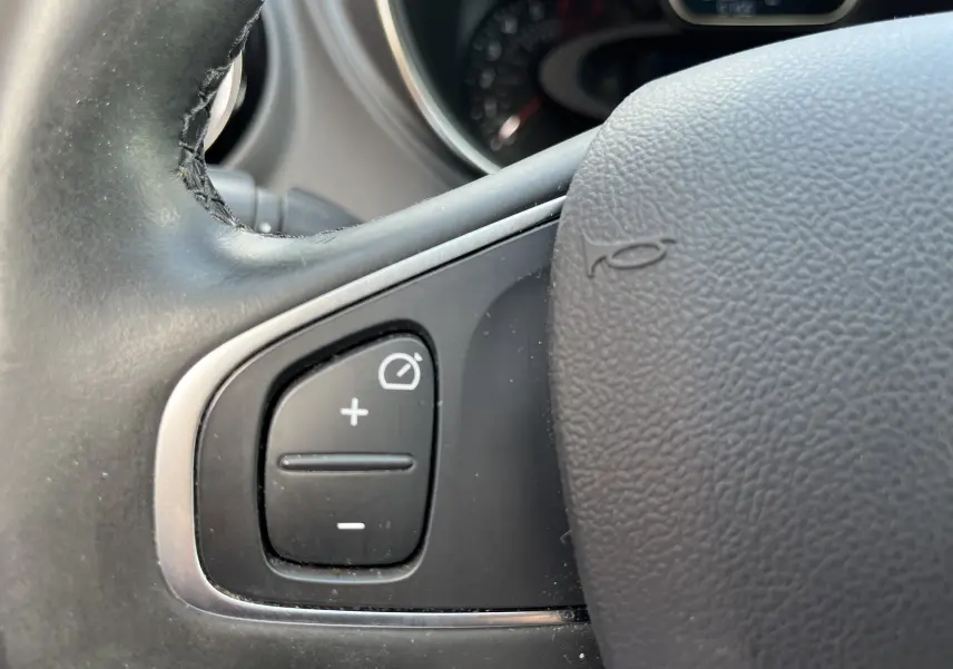 Gros plan sur les commandes de régulateur de vitesse sur le volant cuir noir du Renault Captur gris 2019.