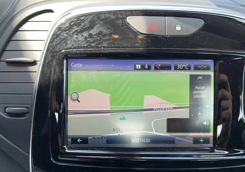 Gros plan sur l'écran tactile du GPS intégré au tableau de bord noir brillant du Renault Captur gris de 2019.
