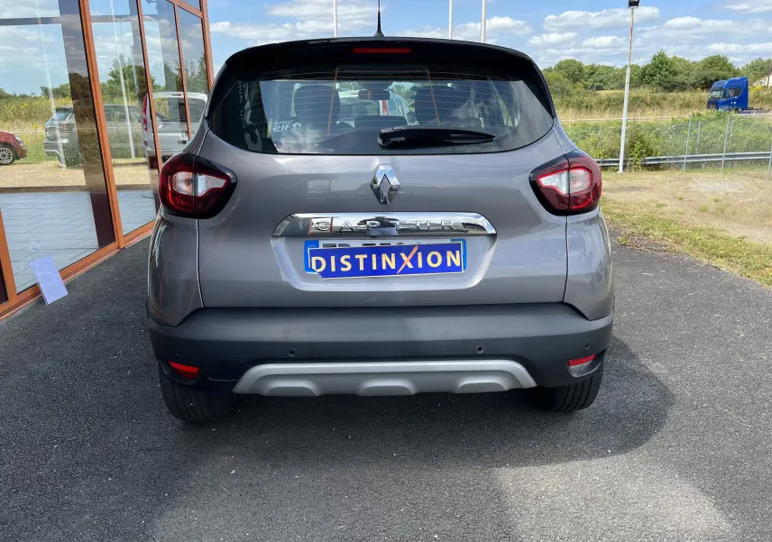 Vue arrière d'un Renault Captur gris 2019 avec logo chromé et plaque d'immatriculation personnalisée "DISTINXION".