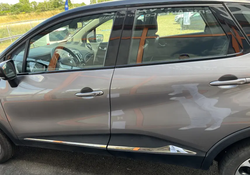 Vue latérale gauche d'un Renault Captur gris 2019 avec détails chromés sur les bas de porte et intérieur visible.