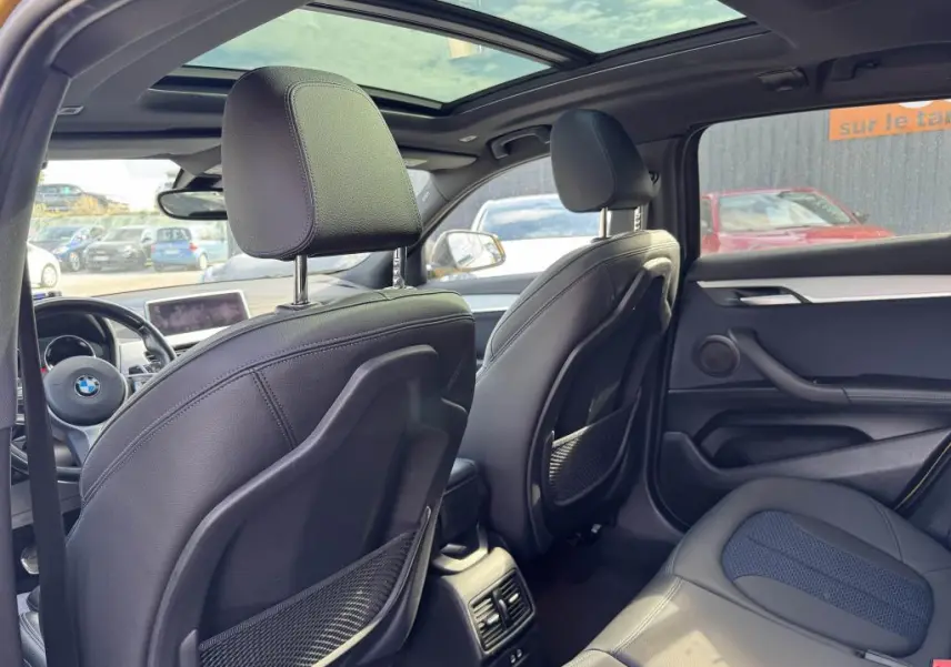 Vue intérieure arrière du BMW X2 M Sport 2021 avec toit ouvrant panoramique et sellerie noire en similicuir et tissu.