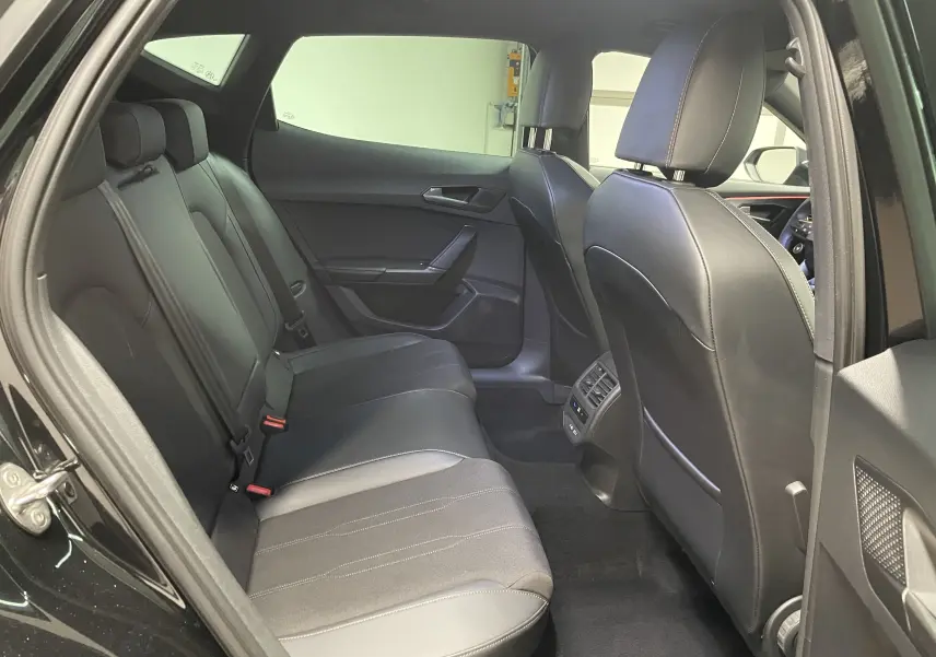 Vue intérieure arrière côté gauche du CUPRA Formentor noir Minuit, montrant les sièges arrière en cuir et les aérateurs centraux.