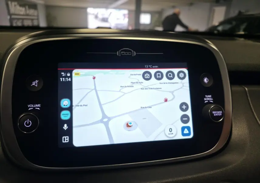 Écran tactile central du tableau de bord de la Fiat 500X 2024 affichant la navigation GPS avec commandes autour.