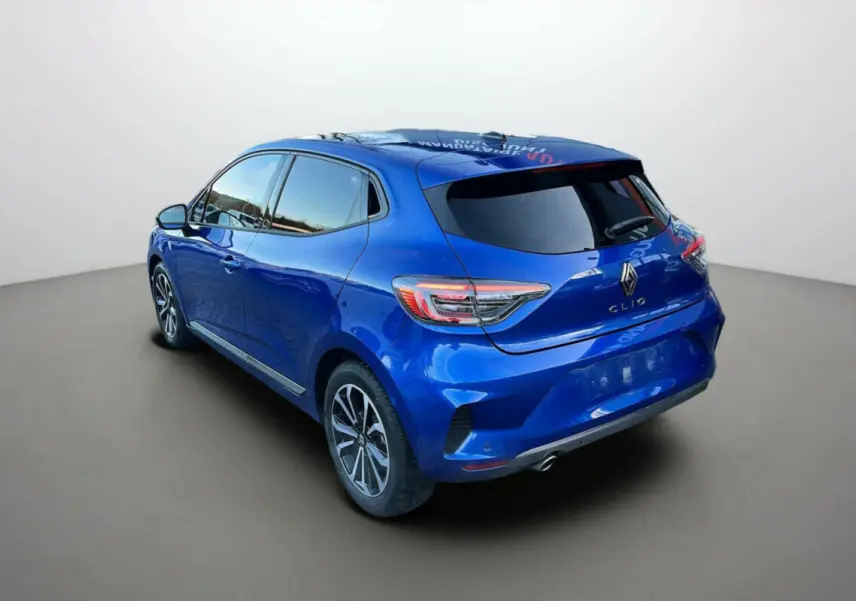 Renault Clio V TCE 90 Techno Plus bleu iron vue 3/4 arrière droit avec vitres surteintées et jantes alu noires.