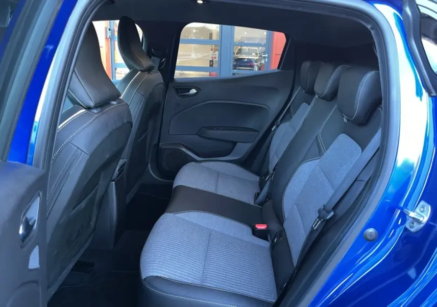 Vue intérieure des sièges arrière gris et noir de la Renault Clio V TCE 90 Techno Plus bleu iron avec porte ouverte côté droit.