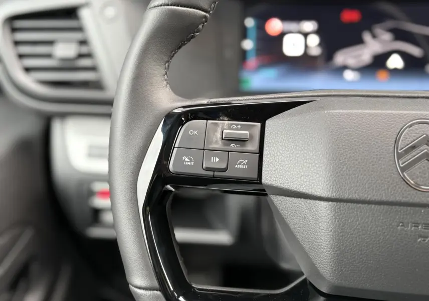 Gros plan sur la partie gauche du volant cuir noir du Citroën Jumpy 2025 avec commandes de régulateur et assistant de conduite.