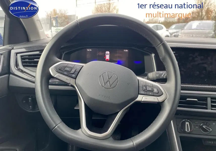 Vue intérieure centrée sur le volant cuir multifonction de la Volkswagen Polo 2025, avec tableau de bord digital en arrière-plan.