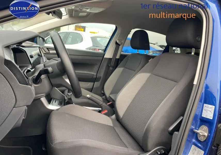 Vue intérieure côté conducteur de la Volkswagen Polo bleu récif, montrant les sièges tissu noir et gris et le volant cuir multifonction.