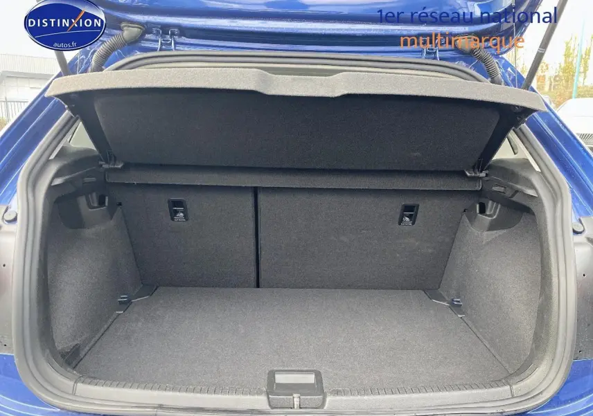 Coffre ouvert vu de l'arrière d'une Volkswagen Polo bleu récif, montrant un espace de rangement propre et spacieux.