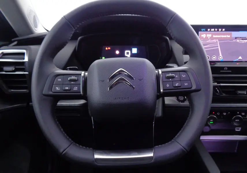 Vue rapprochée du volant cuir noir de la Citroën C5 X 2023 avec commandes intégrées et tableau de bord numérique.