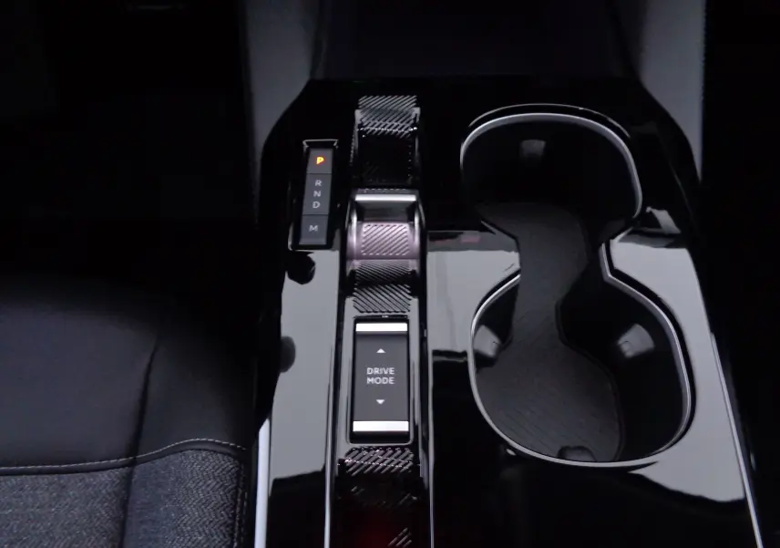 Gros plan sur la console centrale noire brillante de la Citroën C5 X 2023, avec levier de vitesses automatique et porte-gobelets.