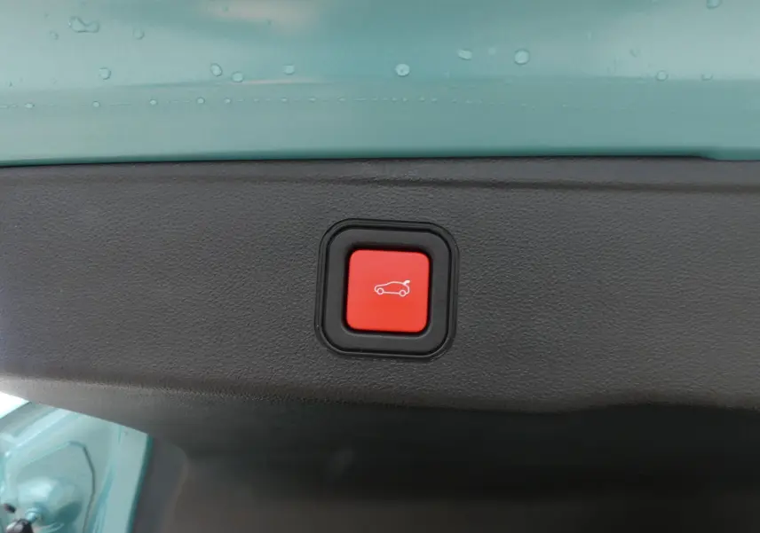 Bouton rouge d'ouverture électrique du hayon sur le bord intérieur d'un Jeep Avenger bleu métallisé 2024.