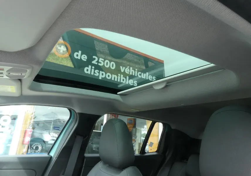 Toit ouvrant électrique en verre vu de l'intérieur arrière d'un Jeep Avenger bleu métallisé 2024