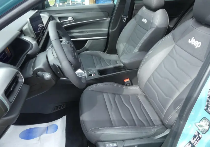 Intérieur avant droit du Jeep Avenger 2024 avec sièges cuir noir brodés Jeep et tableau de bord moderne.