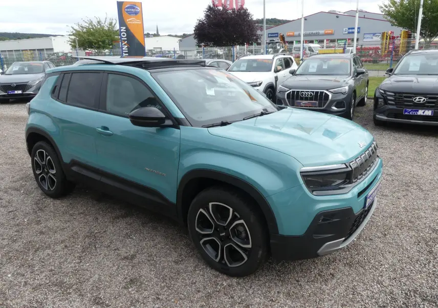 Jeep Avenger bleu métallisé en 3/4 avant droit avec toit noir et jantes alliage 18 pouces sur parking extérieur.