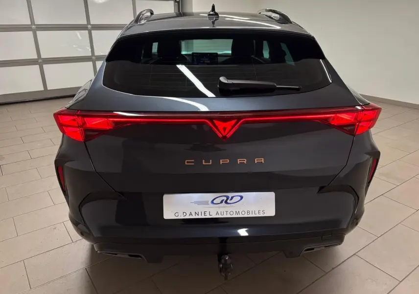 Vue arrière d'un CUPRA Formentor gris magnétique avec feux LED reliés et crochet d'attelage escamotable visible.