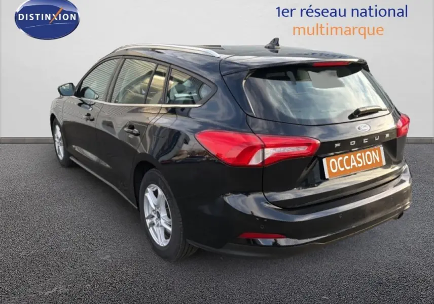 Vue 3/4 arrière droite d'une Ford Focus SW noire de 2019 avec barres de toit et jantes alliage 16 pouces.