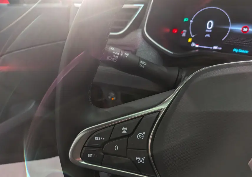 Gros plan sur le volant côté gauche de la Renault Clio V, avec commandes de régulateur et tableau de bord numérique visible.