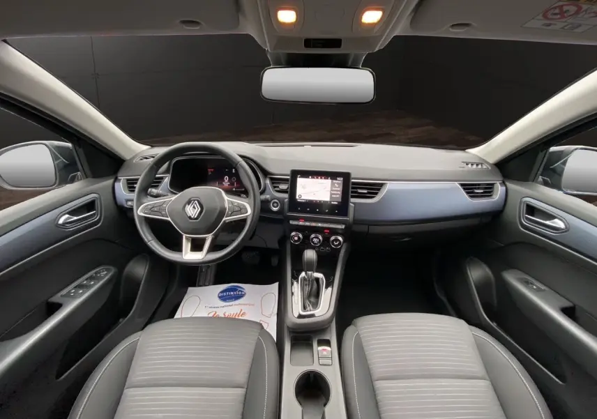 Vue intérieure avant de la Renault Arkana 2024, tableau de bord moderne avec écran tactile et volant multifonction noir.
