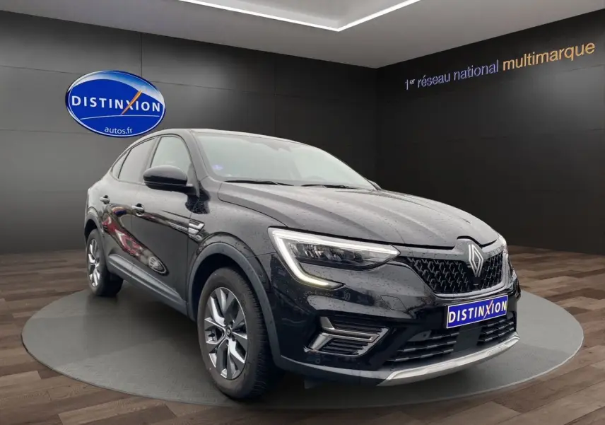Renault Arkana noir vue 3/4 avant droit, avec calandre distinctive et feux LED allumés, en showroom intérieur.