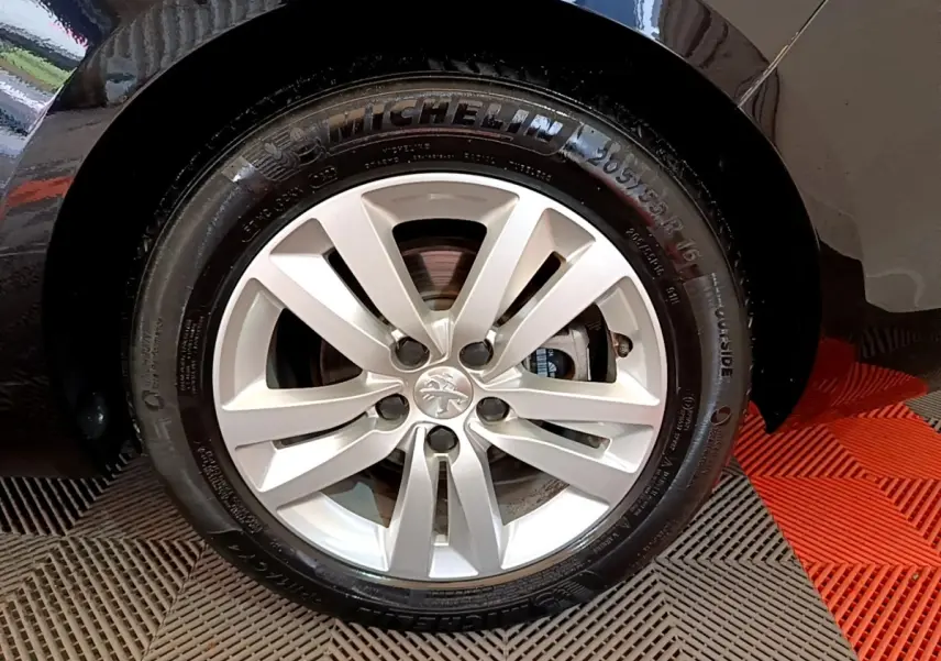 Gros plan sur la roue avant droite avec jante argentée et pneu Michelin sur Peugeot 308 noir.