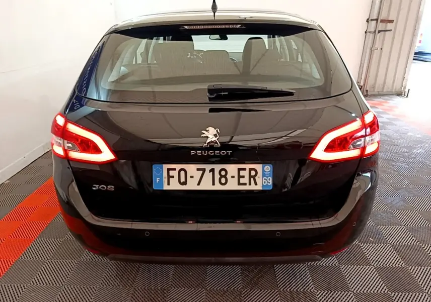 Vue arrière d'une Peugeot 308 noire de 2020 avec feux arrière allumés dans un garage fermé.