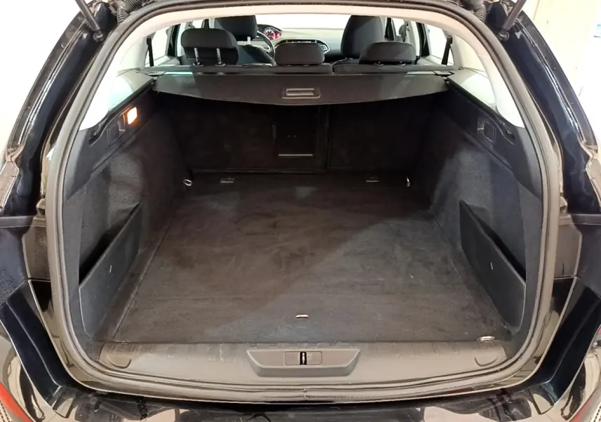 Coffre ouvert d’une Peugeot 308 noire, vue arrière montrant l’espace de chargement et la banquette arrière.