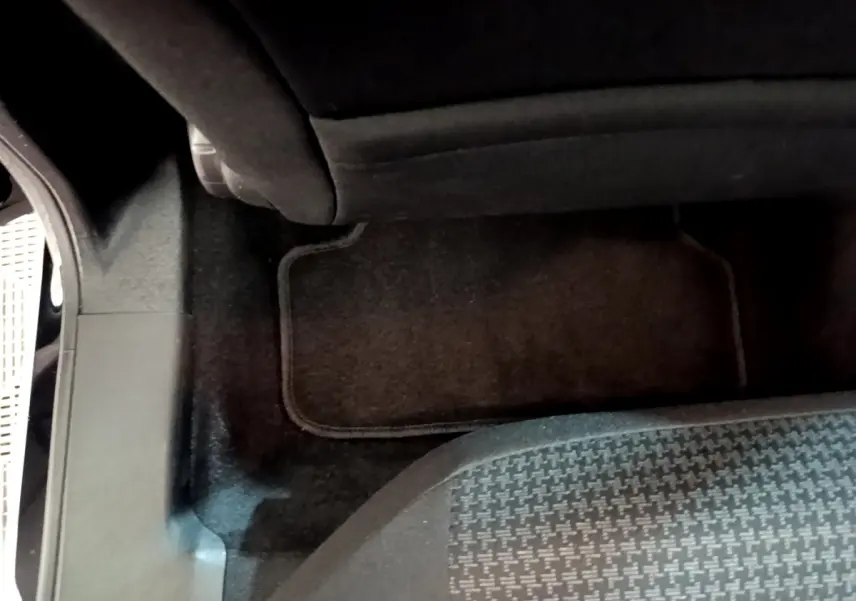 Plancher arrière côté droit avec tapis noir et partie inférieure du siège arrière d’une Peugeot 308 noire 2020.