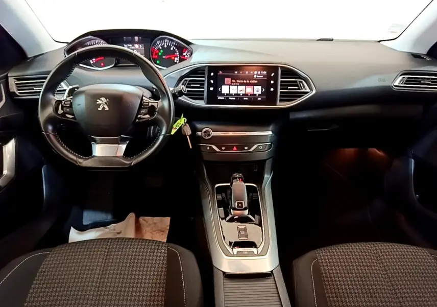 Intérieur de Peugeot 308 2020 vue de face, tableau de bord noir avec écran tactile central et volant cuir multifonctions.