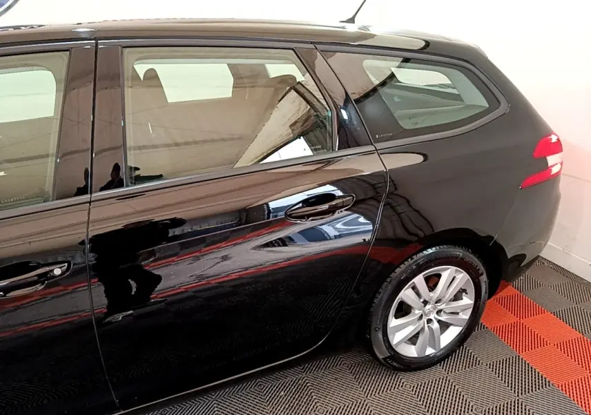 Vue latérale côté droit d'une Peugeot 308 noire de 2020, mettant en valeur les jantes alliage et la carrosserie brillante.