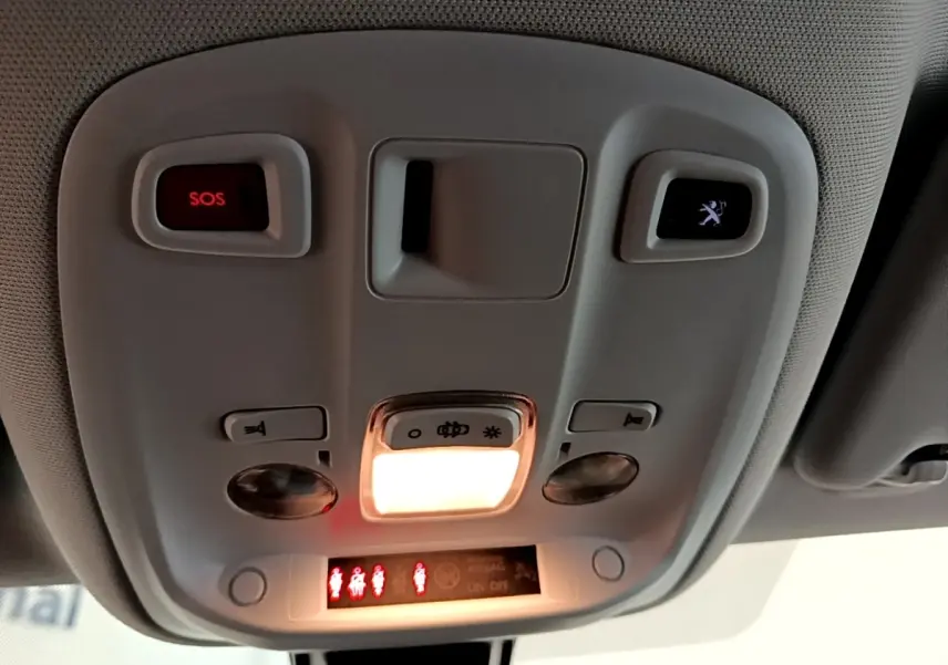 Vue intérieure du plafonnier avant de la Peugeot 308 noire, avec éclairage et boutons SOS et assistance visibles.
