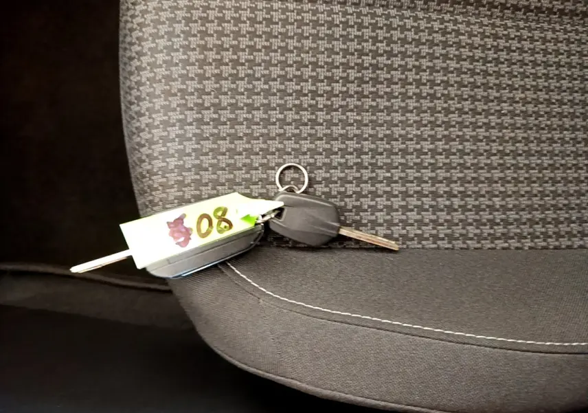 Clé de voiture posée sur le siège avant tissu gris foncé à motifs, intérieur du Peugeot 308 noir 2020.