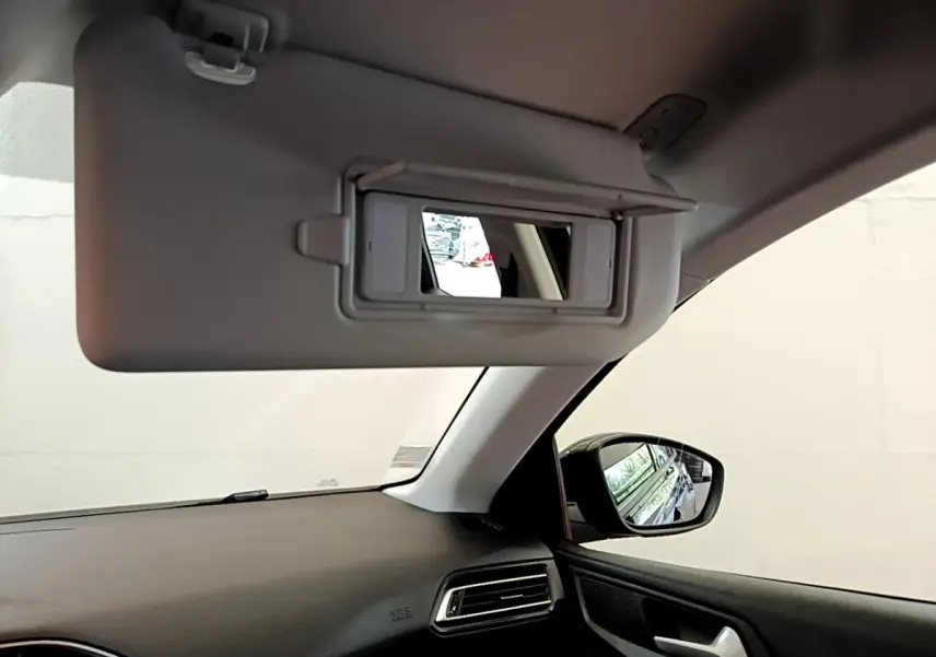 Intérieur de la Peugeot 308 noir, vue côté passager avec pare-soleil relevé et rétroviseur extérieur visible.