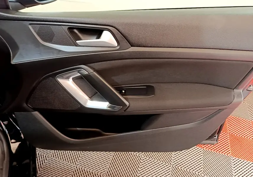 Vue intérieure du panneau de porte côté gauche noir de la Peugeot 308 Active Business 2020 avec poignée argentée.