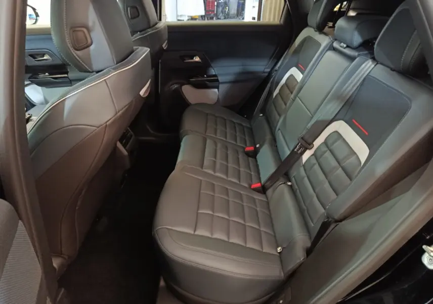 Vue intérieure côté droit des sièges arrière en cuir noir avec surpiqûres et détails gris et rouges du Citroën C5 Hybride 2026.