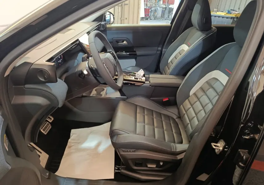 Vue intérieure côté conducteur de la Citroën C5 Hybride noire 2026, sièges cuir et tableau de bord moderne.