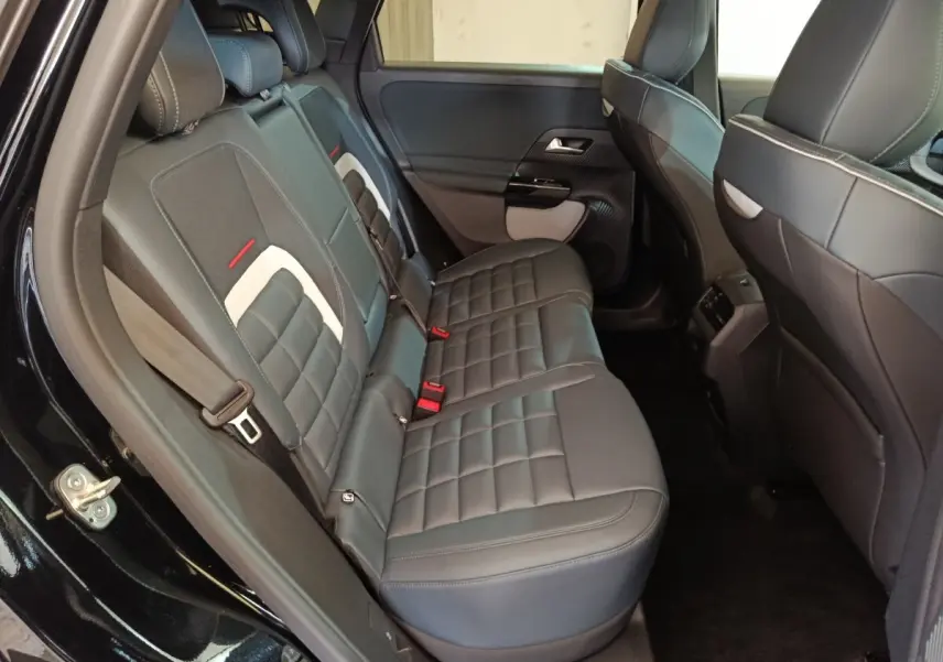 Vue intérieure côté gauche des sièges arrière noirs avec surpiqûres blanches et détails rouges du Citroën C5 Hybride 2026.