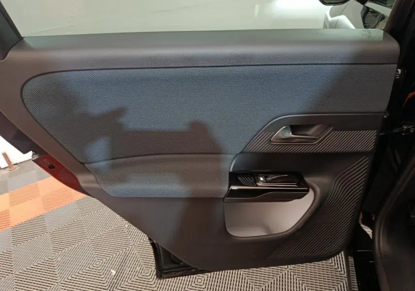 Vue intérieure de la porte arrière gauche noire de la Citroën C5 Hybride 145ch avec habillage texturé et poignée argentée.