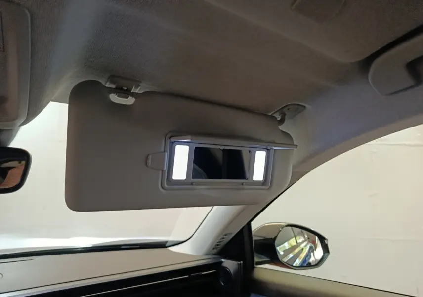 Intérieur de la Citroën C5 Hybride noir, vue côté passager avec pare-soleil rabattue et miroir éclairé.