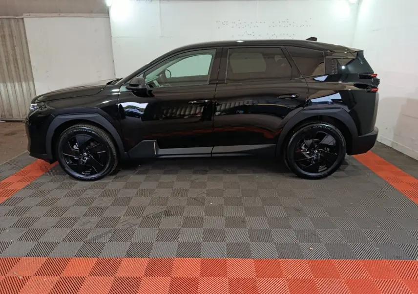 Vue de profil côté gauche d'un Citroën C5 Hybride noir 2026 avec jantes noires et lignes modernes marquées.