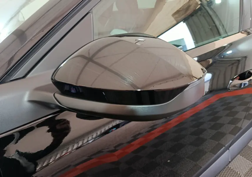 Rétroviseur côté gauche noir brillant de la Citroën C5 Hybride 2026 avec carrosserie noire et poignée visible.