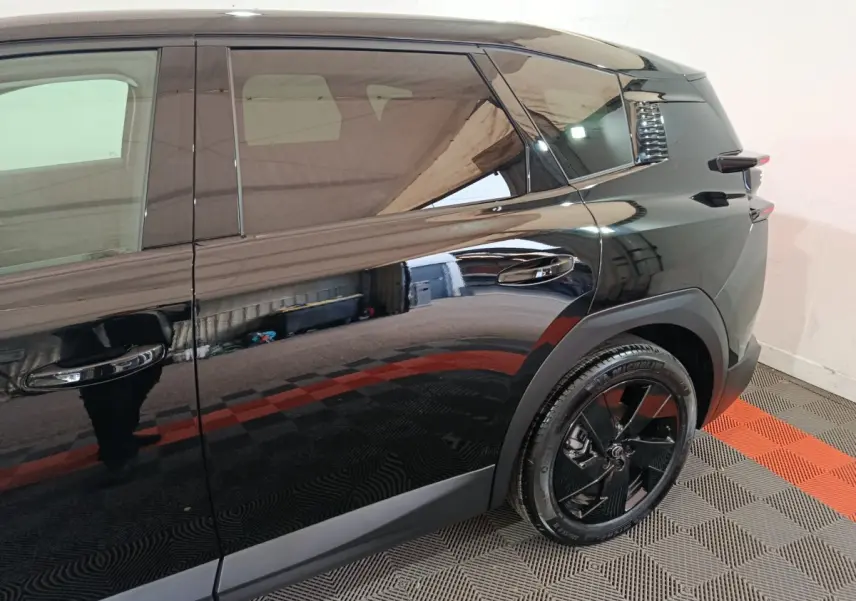 Vue côté droit arrière du Citroën C5 Hybride noir brillant avec jante noire et poignées de porte intégrées.