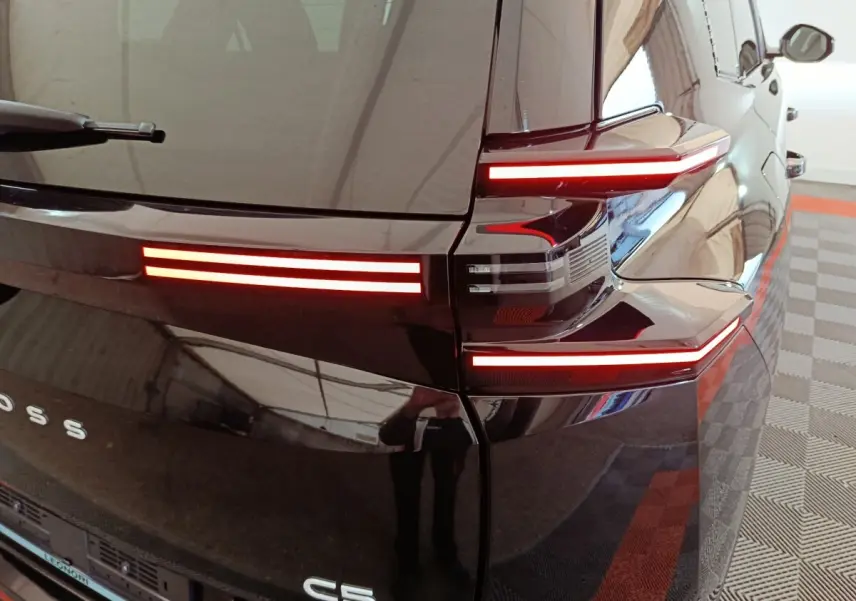 Vue arrière droite d'une Citroën C5 noire 2026 avec feux arrière LED horizontaux distinctifs allumés.