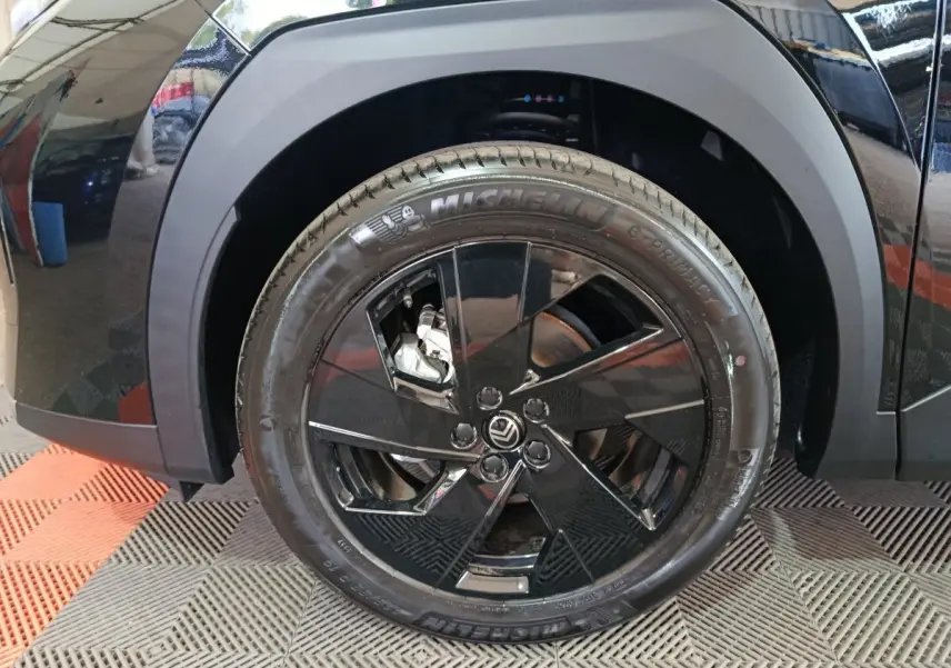 Gros plan sur la roue avant gauche noire d'une Citroën C5 Hybride 2026 avec jante noire brillante et pneu Michelin.