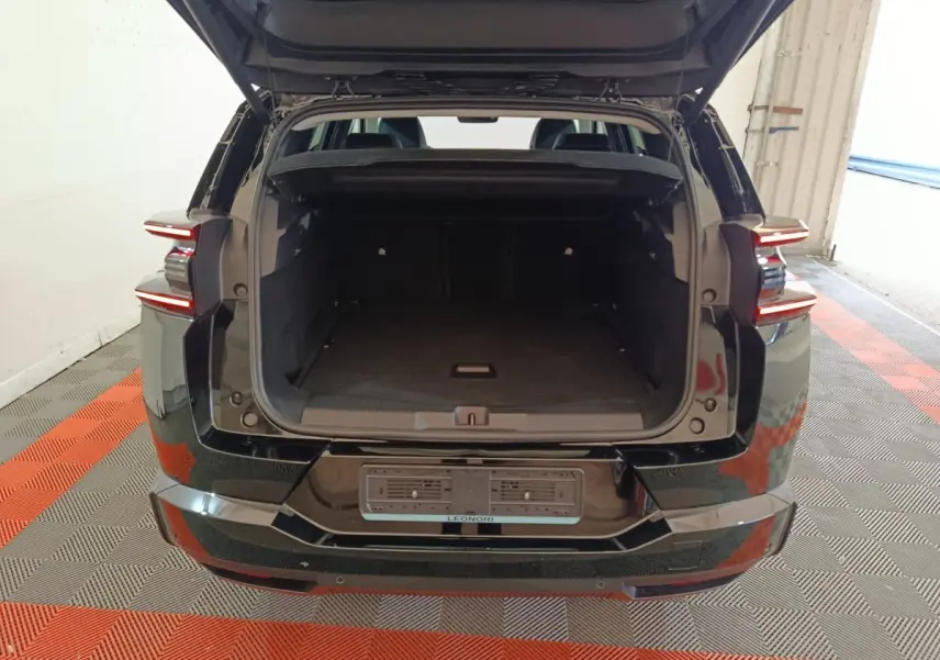 Vue arrière d'un Citroën C5 Hybride noir 2026 avec coffre ouvert et feux arrière LED allumés.