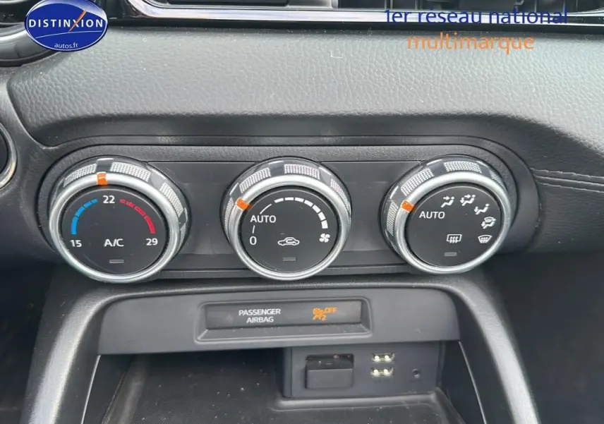 Gros plan sur les commandes de climatisation automatique et l'affichage airbag passager du tableau de bord d'une Fiat 124 Spider Lusso.