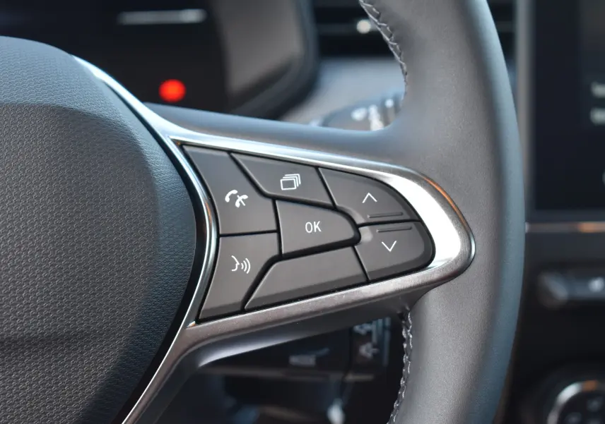Gros plan sur les commandes multifonctions à droite du volant de la Renault Clio V gris 2024, boutons de navigation et appel.