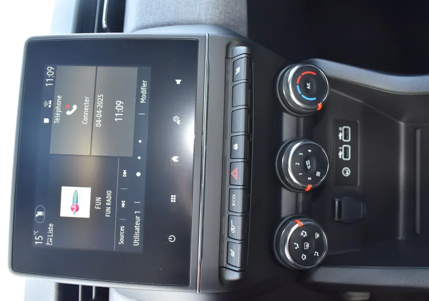 Vue rapprochée du tableau de bord de la Renault Clio V gris, avec écran tactile et commandes de climatisation circulaires.